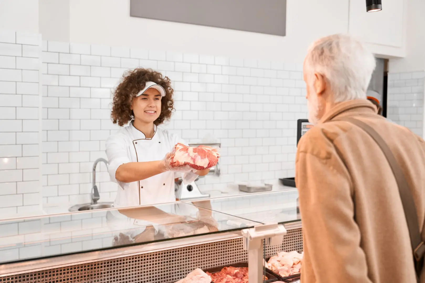 female butcher demonstrating meat eldery man